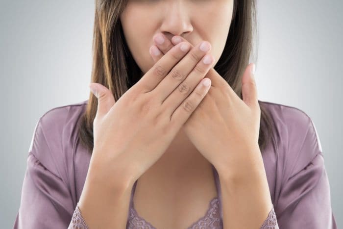 Woman holding her nose, indicating bad breath.