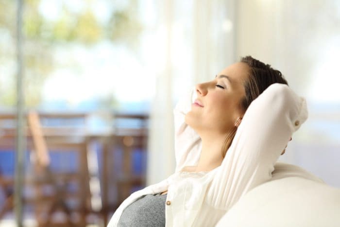 Image of a woman resting on a sofa, eyes closed, smiling.
