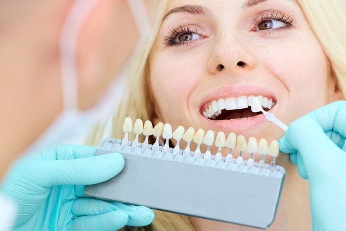 Close-up of a girl examining dental veneers.