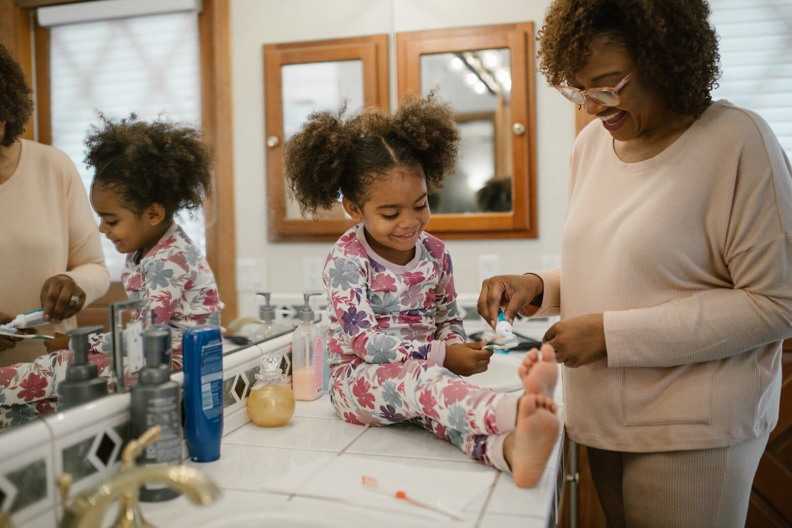 A mother teaching her daughter how to brush teeth
