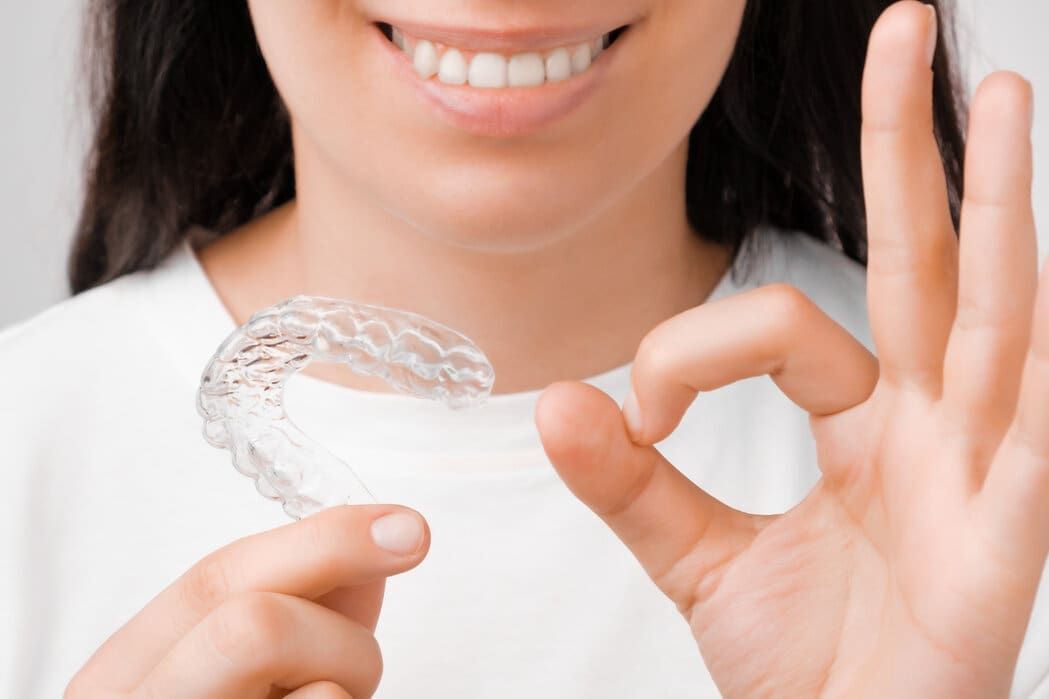 A woman holding Invisalign clear aligners at Sudbury Dental Arts.