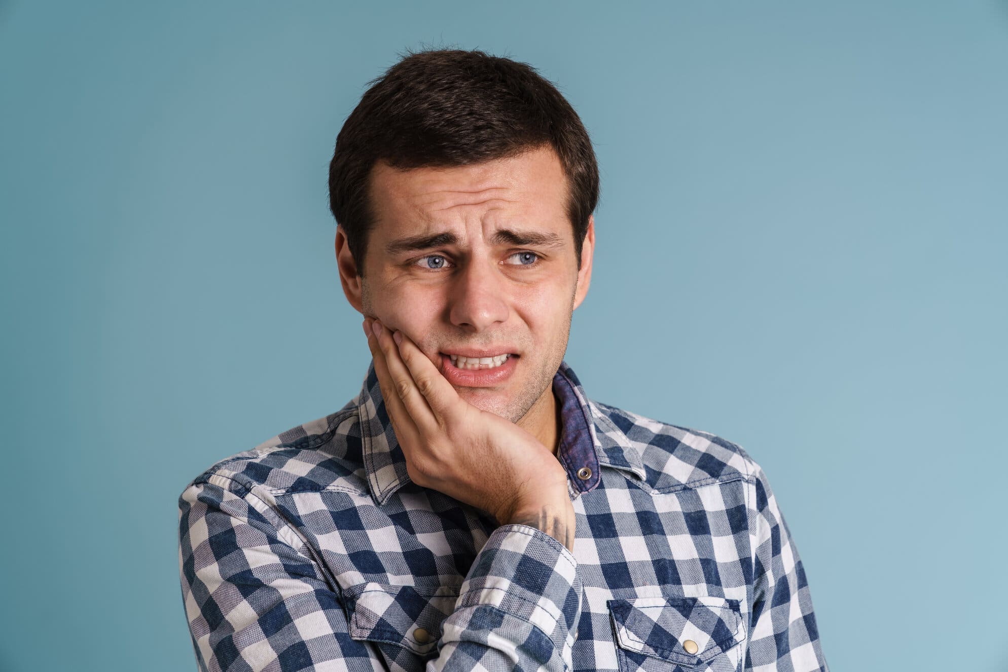 Young man suffering from a tooth ache over blue