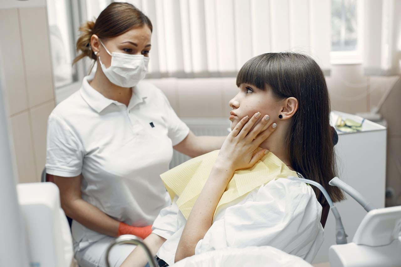 Dentist assisting a female patient with toothache at Sudbury Dental Arts.