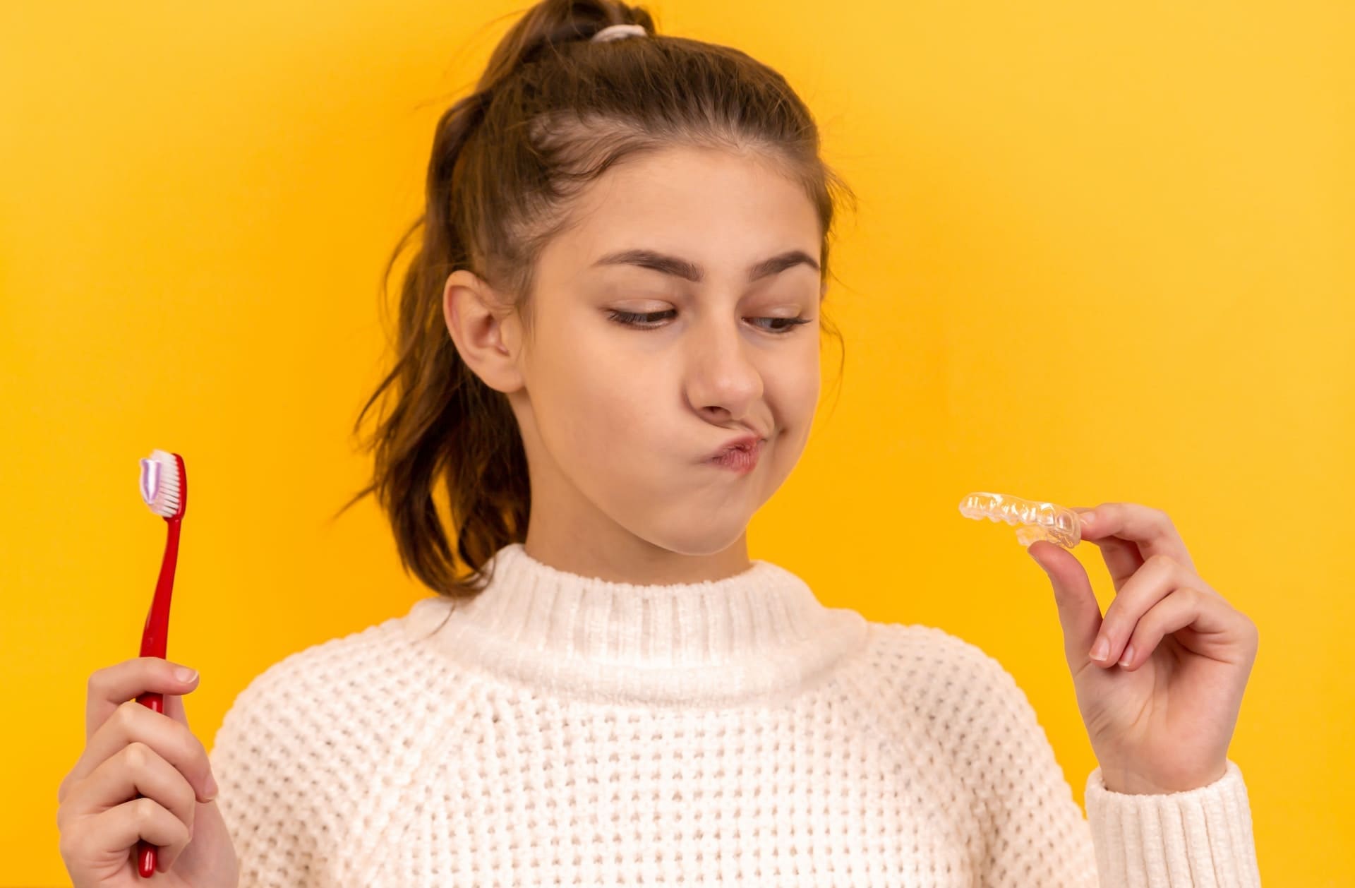 A girl looking at Invisalign clear aligners, considering orthodontic treatment options.