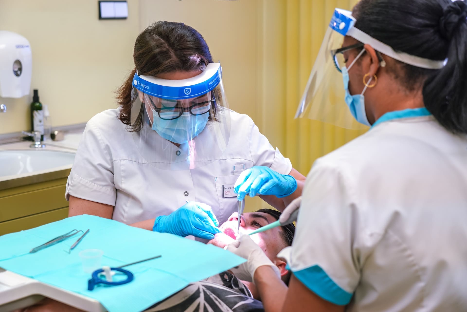 Two dentists providing oral treatment to a patient simultaneously, demonstrating teamwork and efficiency.